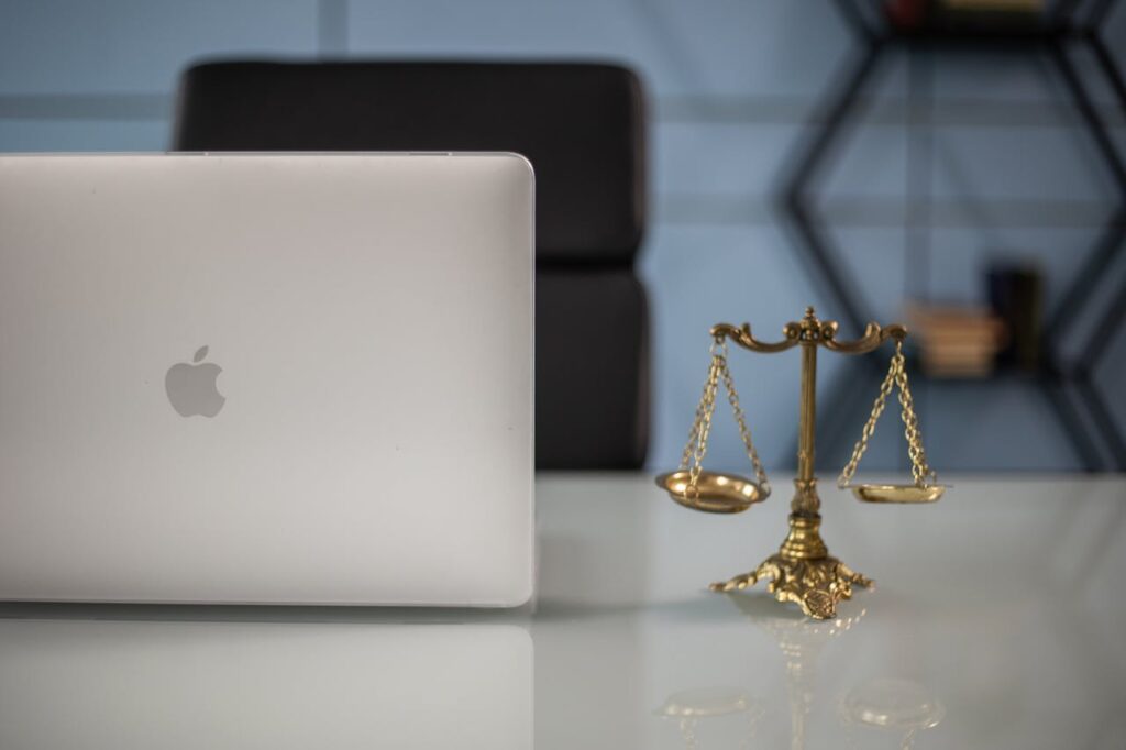 Close-Up Shot of a Laptop beside a Scales of Justice